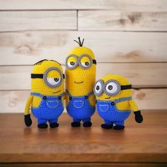 three crocheted minion dolls standing next to each other on a wooden table