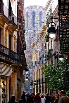 people are walking down the street in front of buildings with balconies on them