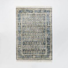 a blue and white area rug with an intricate design on the bottom, in front of a white wall