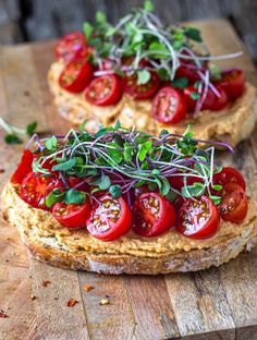 two pieces of bread topped with tomatoes and sprouts