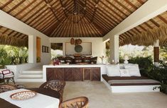 an outdoor living area with wicker furniture and thatched roof over looking the pool