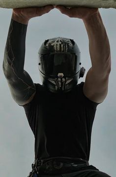 a man in black shirt holding up a white surfboard over his head while wearing a helmet