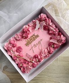 a pink birthday cake in a box with flowers on it and the words happy birthday