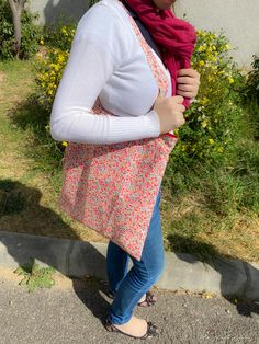 a woman is standing on the sidewalk with her hand in her pocket and wearing a red scarf