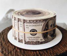 a roll of one hundred dollar bills on top of a piece of wood with a ribbon around it