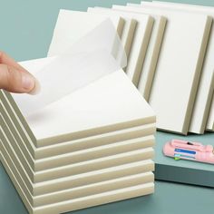 a stack of white cards being held by a person's hand with a pen and eraser next to it