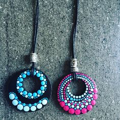 two necklaces with different colored beads hanging from leather cord on concrete surface, closeup