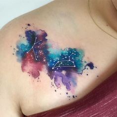 a woman's chest with a colorful tattoo on it and stars in the sky