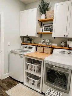 a washer and dryer in a laundry room with white cabinets, wood flooring and open shelving