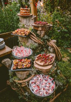 several trays filled with food sitting on top of a table in the grass next to trees