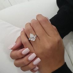 a woman's hand holding a diamond ring