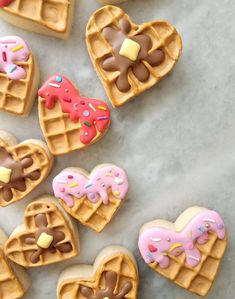 some heart shaped waffles with frosting and sprinkles on them