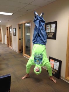 a person upside down in the middle of an office hallway doing a handstand