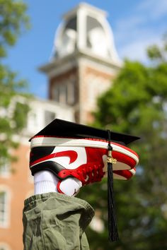 a person wearing a graduation cap and holding a skateboard in front of a building