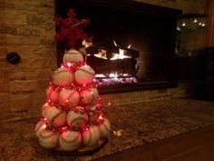 a christmas tree made out of baseballs is lit up in front of a fireplace