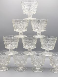 an assortment of glass bowls and cups, all in different shapes and sizes on a grey background