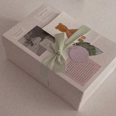 an open box with a green bow on it's side and pictures attached to the lid