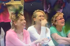 three women laughing while sitting next to each other