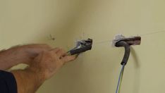 a man is fixing an electrical outlet on the wall with two wires attached to it