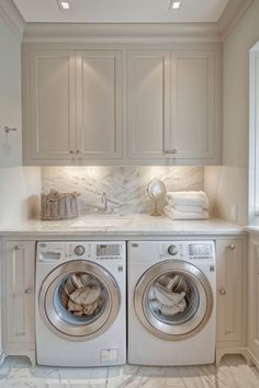 a washer and dryer in a white laundry room with marble counter tops on the floor