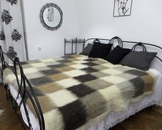 a bed with black and white comforter in a bedroom next to a wall mounted clock