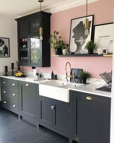 a kitchen with black cabinets and pink walls