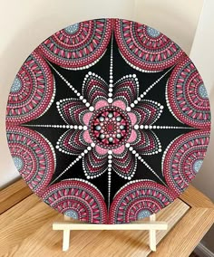 a black and red decorative plate sitting on top of a wooden table next to a white wall