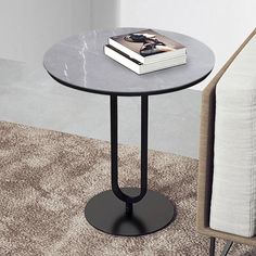 a black table with a book on it next to a white chair and a couch