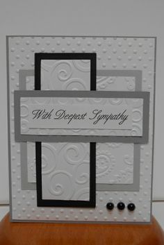 a white card with black and silver accents on the edges that says, wh deepest sympathy