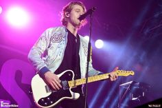 a man with a guitar on stage at a concert