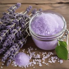 lavender bath salts in a glass jar next to fresh lavender flowers on a wooden table