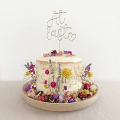 a white cake with flowers on top sitting on a table