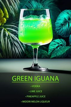 green iguana cocktail with lime and pineapple in front of tropical leaves on black background