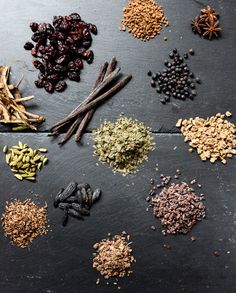 an assortment of spices and herbs laid out on a black surface, including cloves