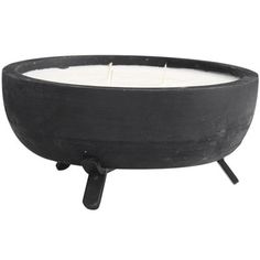 a black bowl with a white candle in it on a stand against a white background