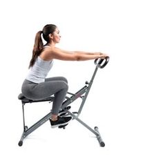 a woman sitting on top of a stationary exercise chair holding the handle bar up to her chest