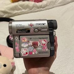 a person holding up a camera with hello kitty stickers on it's side