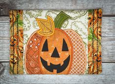 an orange and black pumpkin with a green leaf on it's head is sitting on a wooden surface