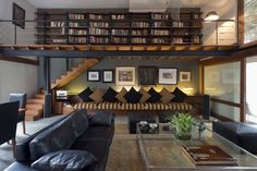 a living room filled with furniture and bookshelves next to a stair case full of books