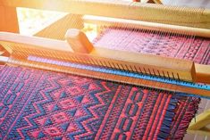 an old weaving machine with red and blue designs on it's warpning needles