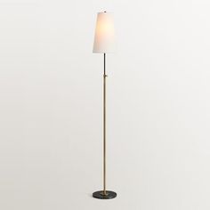 a floor lamp with a white shade on it's side and a black base