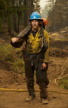 a man wearing a hard hat and carrying a fire hose