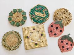 four different types of brooches on a white surface, including strawberries and other decorative items