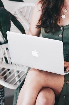 a woman sitting in a chair with an apple laptop