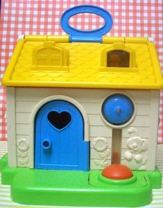 a toy house with a blue door and yellow roof on a checkered table cloth