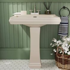 a bathroom sink sitting next to a basket filled with flowers