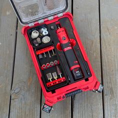 a red tool box filled with tools on top of a wooden floor