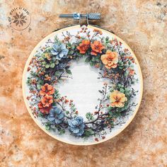 an embroidery hoop with flowers on it sitting on top of a stone floor next to a wall