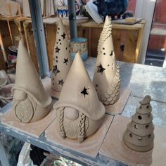 clay sculptures are sitting on a table in front of other pottery items, including hats and trees