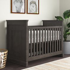 a baby crib with two framed pictures on the wall